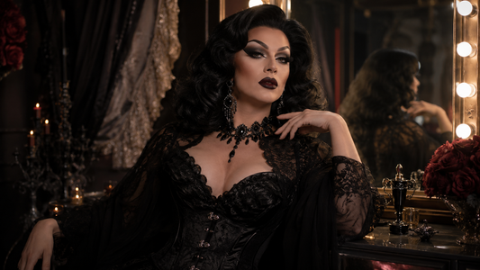 Drag queen in a dark glam look with dramatic makeup, voluminous wig, black sparkling outfit, statement jewelry and theatrical dressing-room lighting.