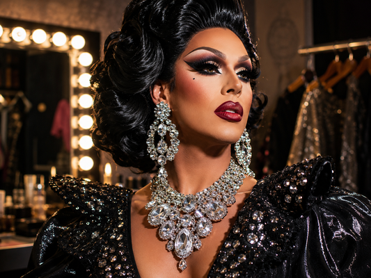 Drag queen choosing dramatic jewelry in front of a vanity mirror with earrings, chokers and crystal accessories.