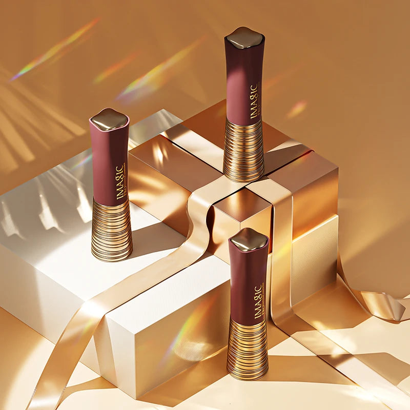 Three lipsticks with gold caps and red-brown shades on a reflective gold surface.